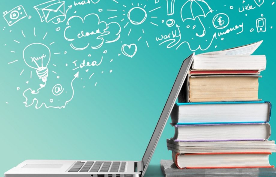 Stack of books with laptop on table